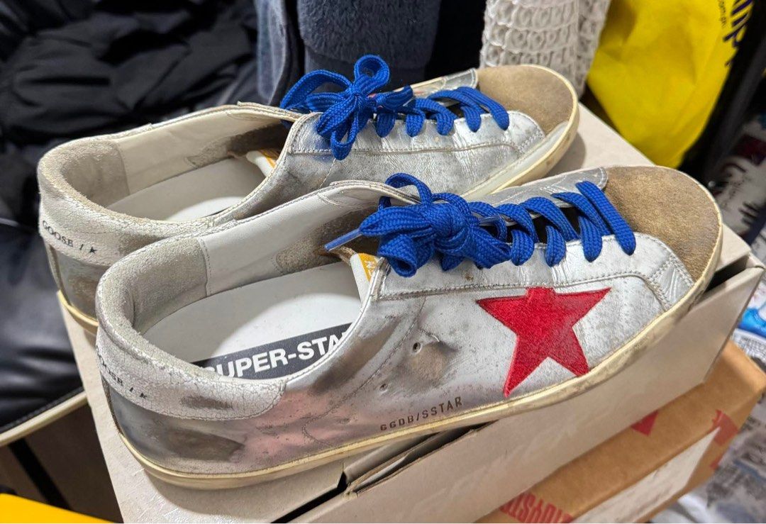 Golden Goose Super-star (Category: Sneakers) located in Manila. Submitted by martin827 (Listing ID 1459523875, Image 3). Description: Silver crackled/laminated leather upper, red signature leather star applique, blue laces, suede toe box, and the brand’s iconic pre-distressed/worn finish.