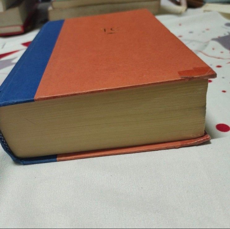 Locked On by Tom Clancy Hardbound Book (Category: Storybooks) located in Quezon City. Submitted by dncpreloved (Listing ID 1459688110, Image 2). Description: - Orange hardcover book with a blue spine. - Gold embossed initials 'TC' on the front cover. - Pages are yellowed with age, indicating a vintage item. - Shows some wear on corners and edges, consistent with age. - Interior pages contain text and page numbers. - A substantial and lengthy read