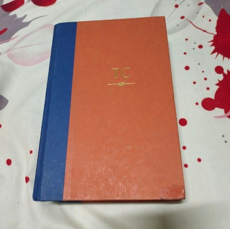 Locked On by Tom Clancy Hardbound Book (Category: Storybooks) located in Quezon City. Submitted by dncpreloved (Listing ID 1459688110, Image 1). Description: - Orange hardcover book with a blue spine. - Gold embossed initials 'TC' on the front cover. - Pages are yellowed with age, indicating a vintage item. - Shows some wear on corners and edges, consistent with age. - Interior pages contain text and page numbers. - A substantial and lengthy read