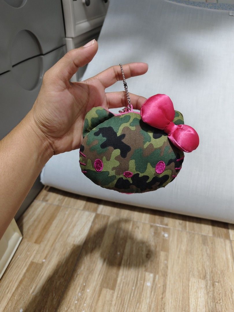 Hello Kitty Camouflage keychain with Mirror (Category: Purses & Pouches) located in Makati City. Submitted by abegailbrezuela (Listing ID 1459615895, Image 1). Description: - Features a cool camouflage print on one side - Soft pink fuzzy interior on the other side - Includes a small pink bow accent - Built-in mirror inside for quick touch-ups - Convenient keychain attachment - Ideal for storing coins, cash, or small essentials - Compact size, per