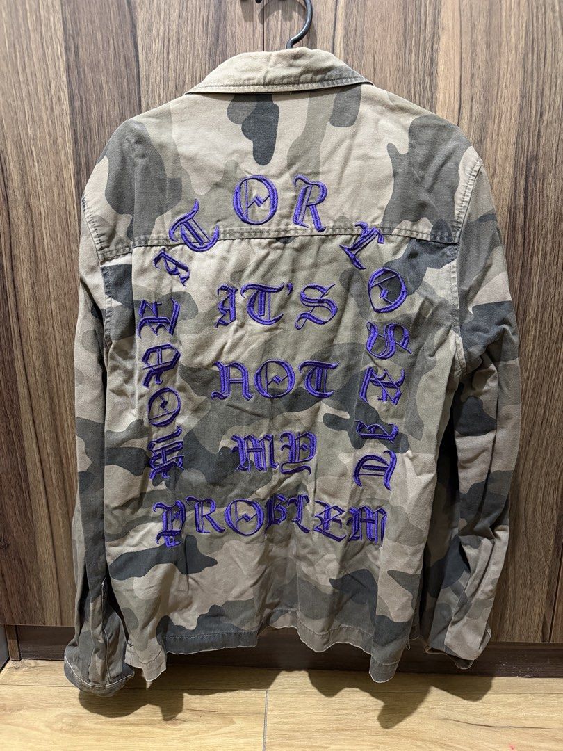 H&M Camo Jacket with Purple Embroidery (Category: Coats, Jackets and Outerwear) located in Taguig. Submitted by plfits (Listing ID 1459663125, Image 2). Description: - H&M Camouflage Jacket - Size: Medium (M) - Bold purple embroidered text on the back - Two chest pockets - Button-up front - Ideal for layering.
