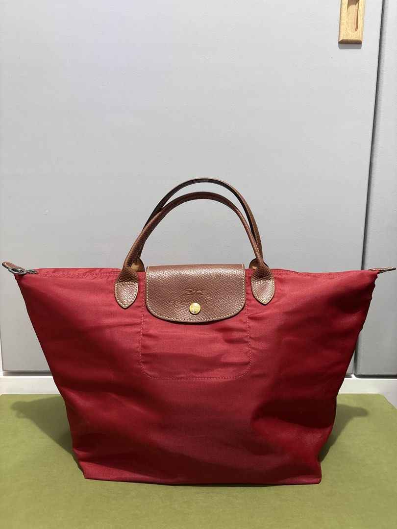 AUTHENTIC Longchamp Le Pliage Tote Bag Red (Category: Luxury Bags & Wallets) located in Subic. Submitted by dear.jeveaph (Listing ID 1459643347, Image 1). Description: - Classic Longchamp Le Pliage tote - Red nylon body - Brown leather handles and trim - Iconic embossed horse logo on leather flap - Zipper closure with snap button - Spacious and lightweight - Perfect for everyday use - No corner holes - Soft nylon needs bag organizer to be stiff F