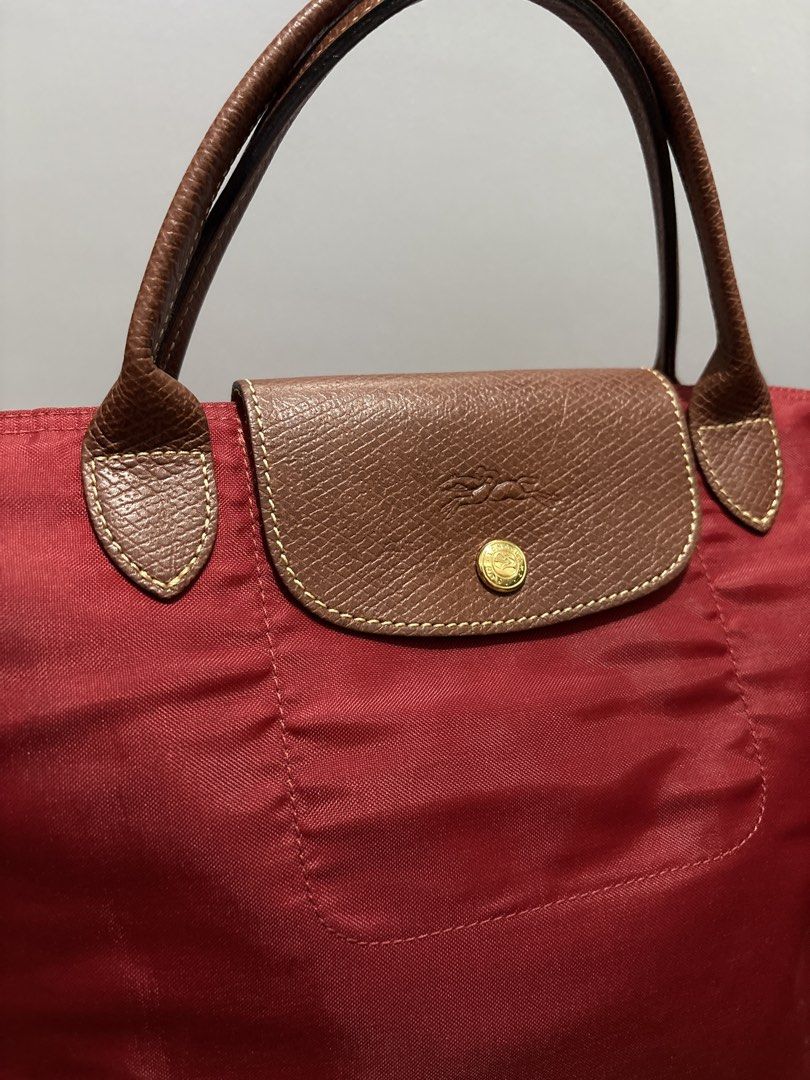 AUTHENTIC Longchamp Le Pliage Tote Bag Red (Category: Luxury Bags & Wallets) located in Subic. Submitted by dear.jeveaph (Listing ID 1459643347, Image 3). Description: - Classic Longchamp Le Pliage tote - Red nylon body - Brown leather handles and trim - Iconic embossed horse logo on leather flap - Zipper closure with snap button - Spacious and lightweight - Perfect for everyday use - No corner holes - Soft nylon needs bag organizer to be stiff F