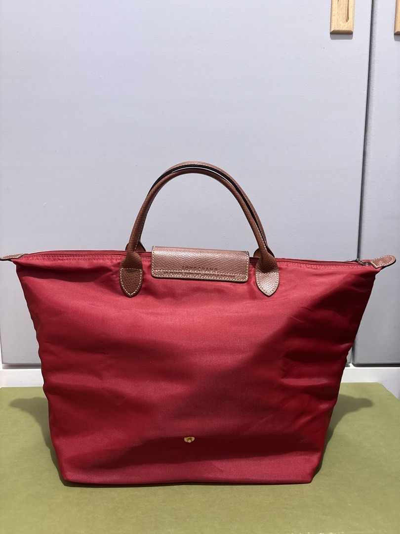 AUTHENTIC Longchamp Le Pliage Tote Bag Red (Category: Luxury Bags & Wallets) located in Subic. Submitted by dear.jeveaph (Listing ID 1459643347, Image 2). Description: - Classic Longchamp Le Pliage tote - Red nylon body - Brown leather handles and trim - Iconic embossed horse logo on leather flap - Zipper closure with snap button - Spacious and lightweight - Perfect for everyday use - No corner holes - Soft nylon needs bag organizer to be stiff F