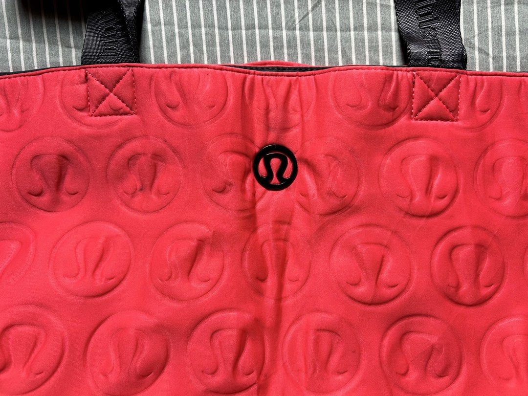Lululemon Red Embossed Logo XL Tote Bag (Category: Tote Bags) located in Bambang. Submitted by mythriftstyle (Listing ID 1459556762, Image 2). Description: •Size 23"x23" •Vibrant Neon/Hot pink Lululemon tote bag •All-over embossed Lululemon logo pattern •Durable black straps with Lululemon branding •Convenient snap closure on handles •wear it black-out or flip it to Hot pink with an all-over embossed logo print. •Two zippered pockets on the front