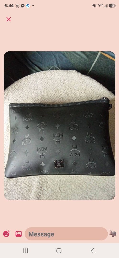 MCM Pouch Clutch Bag Monogram (Category: Luxury Bags & Wallets) located in Aguilar. Submitted by rica040104 (Listing ID 1459660073, Image 2). Description: - Authentic MCM pouch - All-over signature monogram print - Unique blue and white geometric design on front - Zipper closure - Versatile: use as a clutch or bag organizer - Dimensions: approximately 10 inches wide.