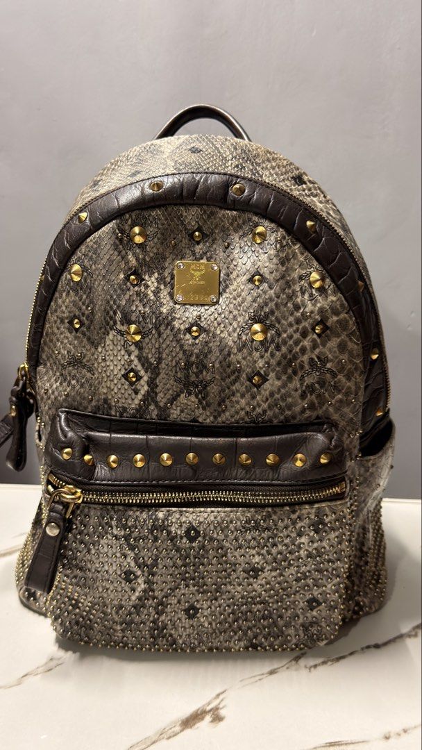 MCM Snakeskin Studded Backpack (Category: Luxury Bags & Wallets) located in Manila. Submitted by faye_preloved (Listing ID 1459602020, Image 1). Description: - Stylish MCM backpack with a cool snakeskin print and elegant gold studs. - Iconic MCM logo pattern visible both inside and outside. - Convenient front zip pocket for quick access. - Adjustable straps for a comfortable fit. - Interior includes a secure zip pocket and multiple slip pockets f