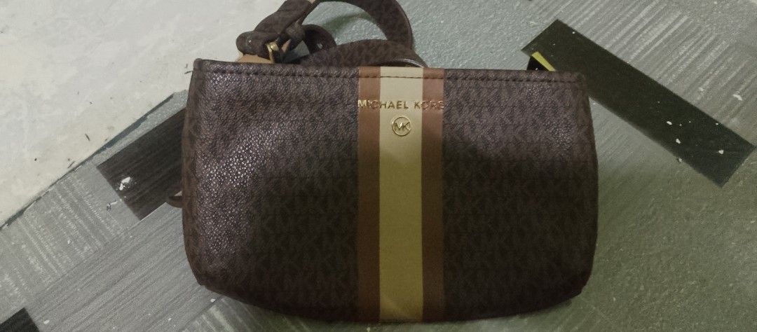 Michael Kors Monogram Pouch with Stripe Detail (Category: Purses & Pouches) located in Manila. Submitted by bunshoy09 (Listing ID 1459555654, Image 1). Description: - Authentic Michael Kors pouch - Signature MK monogram pattern - Beige and brown vertical stripe detail on front - Small attached strap - Ideal for organizing essentials or as a small clutch.