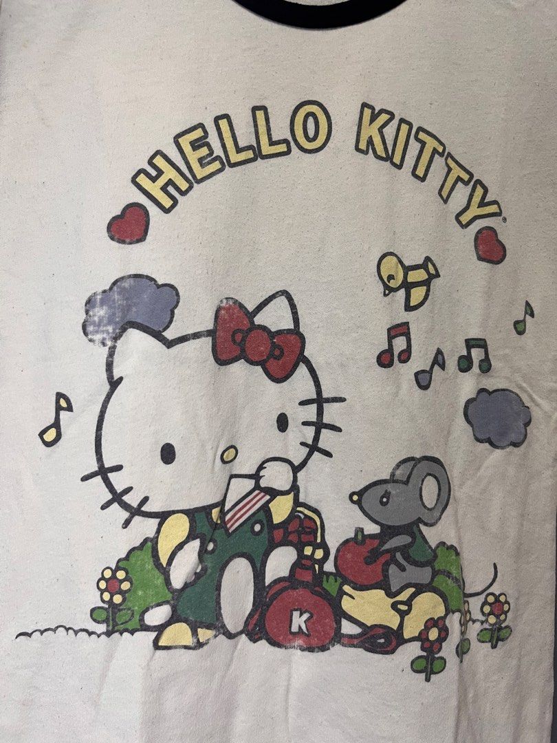 Mighty Fine Hello Kitty T-shirt (Category: Shirts) located in Cabuyao City. Submitted by bulandos (Listing ID 1459633825, Image 2). Description: - Cream colored t-shirt with fun Kitty graphic - Black ringer neck and striped sleeves - Brand: Mighty Fine - Perfect for Kitty fans.