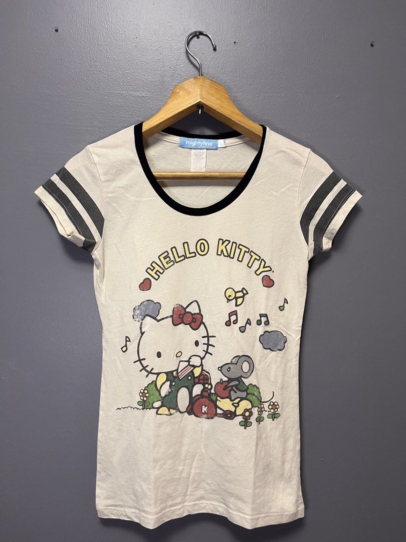 Mighty Fine Hello Kitty T-shirt (Category: Shirts) located in Cabuyao City. Submitted by bulandos (Listing ID 1459633825, Image 1). Description: - Cream colored t-shirt with fun Kitty graphic - Black ringer neck and striped sleeves - Brand: Mighty Fine - Perfect for Kitty fans.