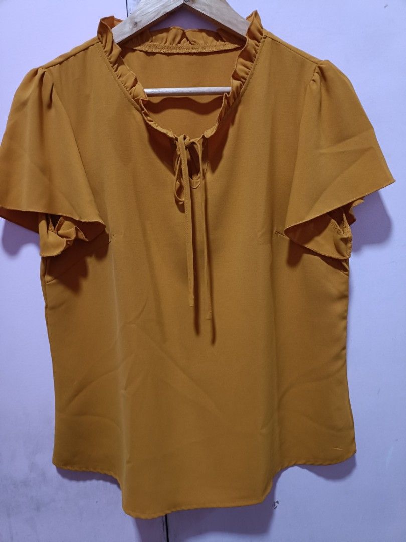 Mustard Yellow Ruffled Neck Tie-Front Flutter Sleeve Top (Category: Blouses) located in Malabon City. Submitted by coollion.15fe1d (Listing ID 1459654857, Image 1). Description: - Adorable mustard yellow top - Features a ruffled neckline with a tie front - Charming flutter sleeves - Versatile for casual outings or dressing up - Easily pairs with jeans or skirts - Flattering fit.