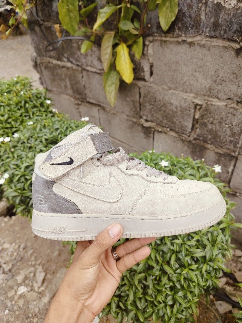 Nike Air Force 1 High Top Suede Sneakers (Category: Sneakers) located in Davao. Submitted by urhandsome_hb (Listing ID 1459566237, Image 3). Description: - Nike Air Force 1 High x Reigning Champ - Color: Light beige/grey suede - Classic Air Force 1 silhouette - Features a velcro ankle strap - Nike Air logo on tongue and heel - Perfect for everyday casual wear.