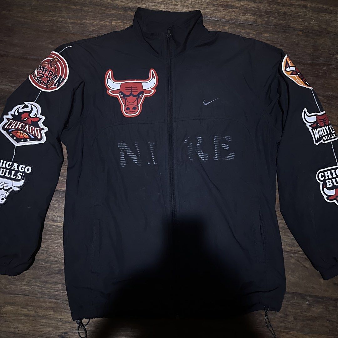 Nike Chicago Bulls Windbreaker Jacket (Category: Coats, Jackets and Outerwear) located in Manila. Submitted by mik1_ (Listing ID 1459550191, Image 2). Description: - Authentic Nike Chicago Bulls Windbreaker Jacket - Size: [Insert Size Here] - Features prominent Chicago Bulls logo on the back - "Chicago" script detailing on the back - Multiple team logos embroidered on the sleeves - Classic Nike logo on the front - Full zipper closure for easy wea