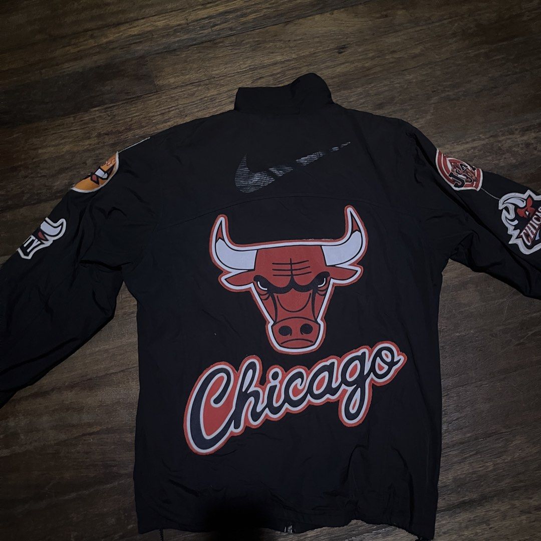 Nike Chicago Bulls Windbreaker Jacket (Category: Coats, Jackets and Outerwear) located in Manila. Submitted by mik1_ (Listing ID 1459550191, Image 1). Description: - Authentic Nike Chicago Bulls Windbreaker Jacket - Size: [Insert Size Here] - Features prominent Chicago Bulls logo on the back - "Chicago" script detailing on the back - Multiple team logos embroidered on the sleeves - Classic Nike logo on the front - Full zipper closure for easy wea