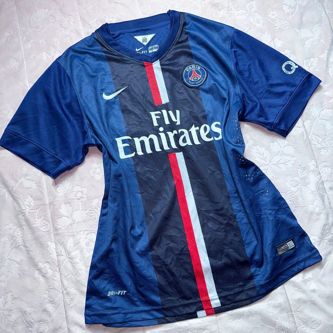 NIKE Fly Emirates Soccer Jersey (Category: Shirts) located in San Fernando. Submitted by rianne_von (Listing ID 1459615041, Image 2). Description: Size L on tag W: 20 in L: 27 in info: ✧ navy blue Paris Saint-Germain Nike Dri-FIT jersey w/ classic red + white center stripe ✧ Fly Emirates sponsor graphic + “ERIC 12” player print at the back ✧ very good thrifted condition; visible cracking/wear on the back name and number prints ✧ color may vary sl