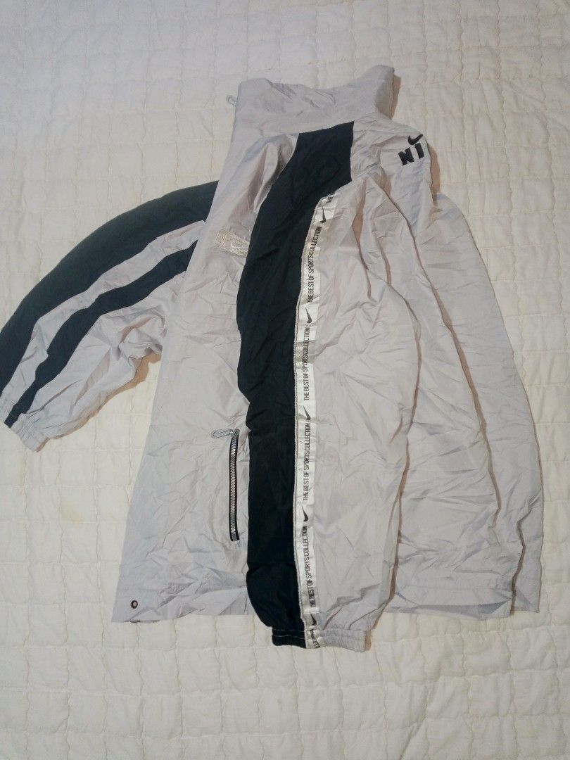 Nike Windbreaker Jacket Grey Black (Category: Coats, Jackets and Outerwear) located in Allen. Submitted by milyonaryung_gipit (Listing ID 1459517906, Image 3). Description: - Authentic Nike windbreaker jacket - Stylish grey body with contrasting black sleeves and accents - Features iconic Nike logo on both chest and back - Convenient zip-up front closure - Includes practical pockets for essentials - Unique 'The Best of Sports Collection' tape det