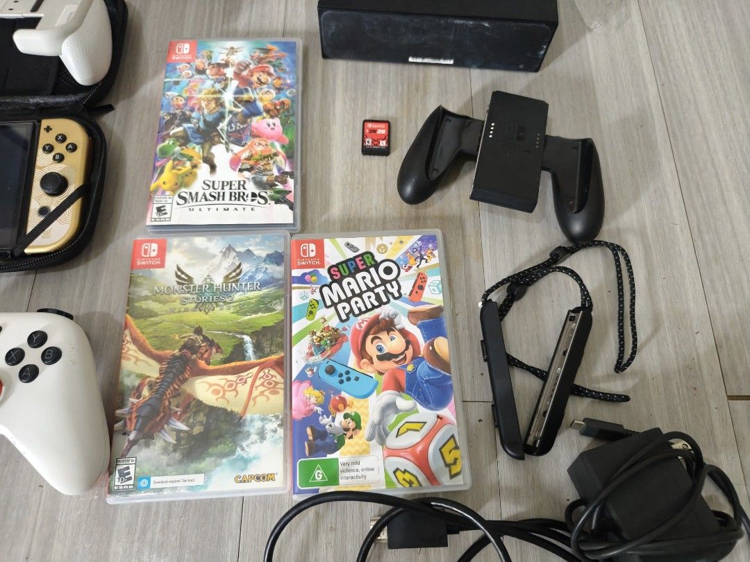 Nintendo Switch OLED Console with Games & Accessories (Category: Nintendo) located in Manila. Submitted by chiki_chem (Listing ID 1459537714, Image 2). Description: - Nintendo Switch OLED Model - Games included: Super Smash Bros. Ultimate, Monster Hunter Stories, Mario Party, Tomodachi Life - White dock - Two pairs of Joy-Cons (pink and white) - Black grip - All necessary cables.