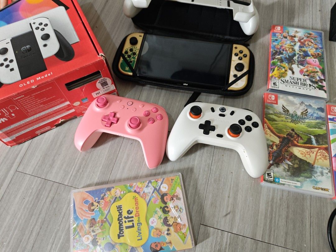 Nintendo Switch OLED Console with Games & Accessories (Category: Nintendo) located in Manila. Submitted by chiki_chem (Listing ID 1459537714, Image 3). Description: - Nintendo Switch OLED Model - Games included: Super Smash Bros. Ultimate, Monster Hunter Stories, Mario Party, Tomodachi Life - White dock - Two pairs of Joy-Cons (pink and white) - Black grip - All necessary cables.