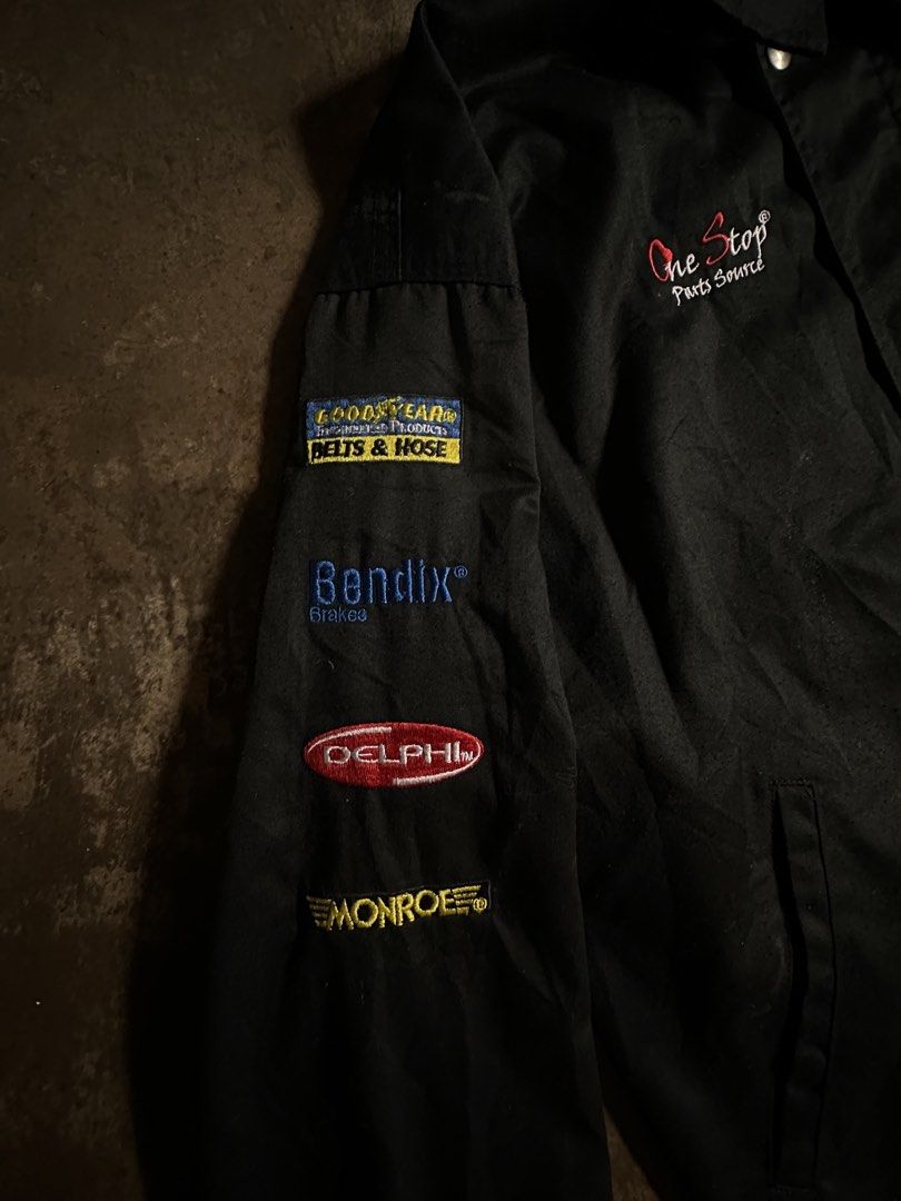One Stop Parts Source Racing Jacket (Category: Coats, Jackets and Outerwear) located in Laoag. Submitted by keenforest-6bd6 (Listing ID 1459532581, Image 2). Description: - Black racing jacket from One Stop Parts Source. - Features embroidered patches on sleeves: Goodyear, Bendix, Delphi, Monroe. - Classic snap button closure. - Ideal for car enthusiasts and collectors..