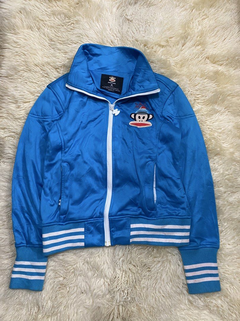 Paul Frank Blue Track Jacket with Julius Logo (Category: Coats, Jackets and Outerwear) located in Manila. Submitted by sepamorash53558 (Listing ID 1459689174, Image 1). Description: - Cool blue Paul Frank track jacket - Features iconic Julius monkey graphic on chest - Zip-up front with convenient pockets - Ribbed cuffs and hem with stylish white and pink stripes - Size: Medium (M) - Ideal for everyday casual wear.