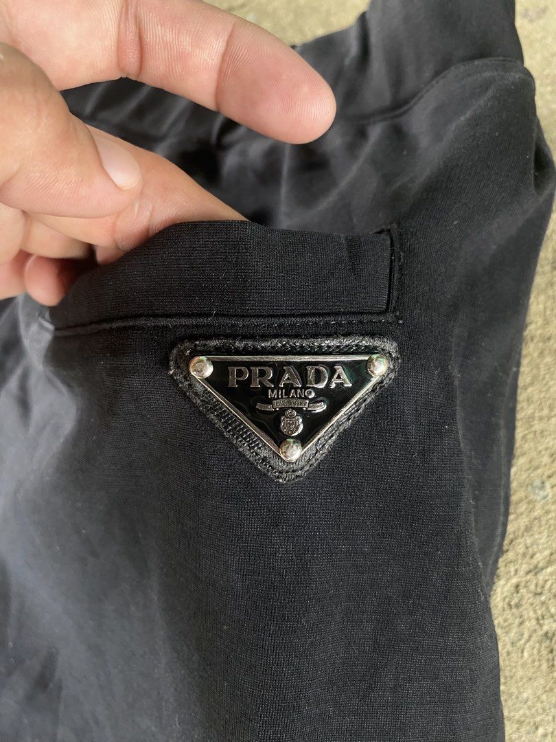 Prada Black Nylon Track Pants Joggers Size XL (Category: Joggers) located in Sinait. Submitted by rinzuthrift (Listing ID 1459528895, Image 3). Description: - Authentic Prada track pants - Size: XL - Material: Nylon and polyester blend - Features: Elastic waistband with drawstring, zipped front pockets - Iconic Prada triangle logo on the back pocket - Perfect for stylish casual wear - Missing zip puller.