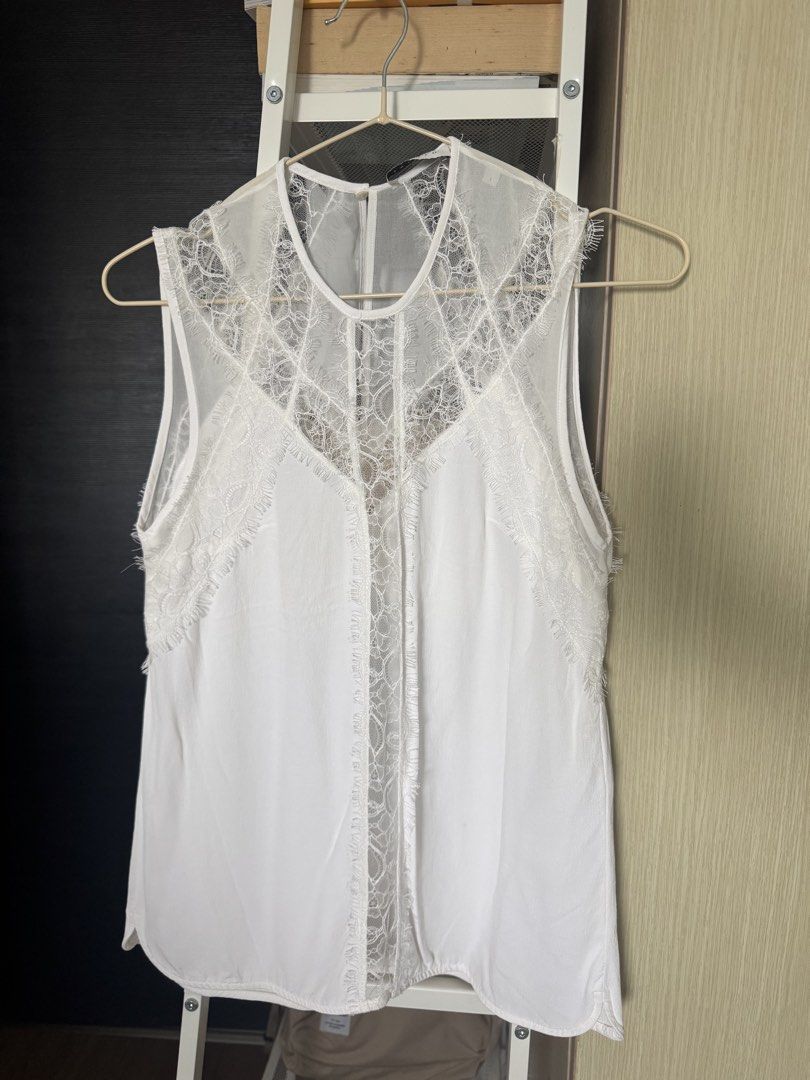 Sandro Paris White Lace Sleeveless Top (Category: Sleeveless) located in Taguig. Submitted by sakuraaaaa____ (Listing ID 1459542330, Image 1). Description: - Size 1 on Tag. Loose fit. XS-S - like new, no issues. - RFS: decluttering - White sleeveless top from Sandro Paris - Features intricate lace detailing on the yoke and front panel - Sheer lace overlay with a solid white underlay - Frayed lace trim along the edges - Button closure at the back 