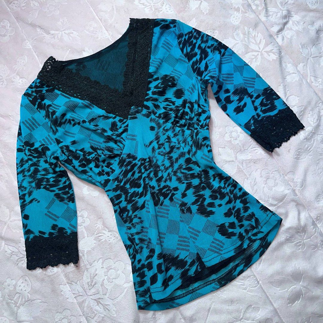Teal Floral Lace Top (Category: Longsleeves) located in San Fernando. Submitted by rianne_von (Listing ID 1459622211, Image 2). Description: W: 14.5 in L: 20.5 in info: ✧ vibrant teal colorway w/ black floral + plaid-inspired print ✧ deep V-neckline w/ black lace trim and matching lace cuffs ✧ excellent thrifted condition; no holes, stains, or major flaws observed ✧ color may vary slightly due to lighting.