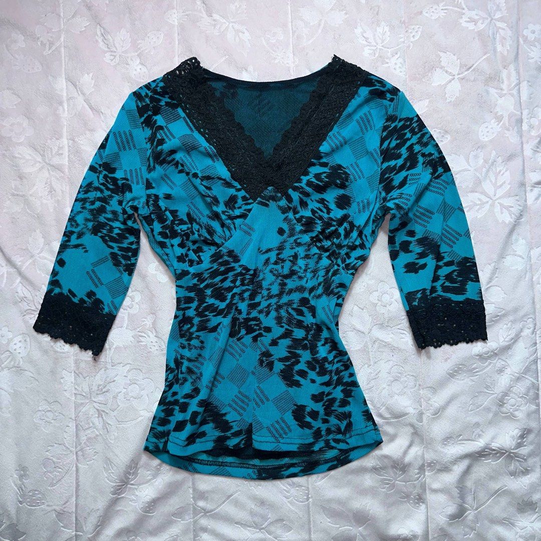 Teal Floral Lace Top (Category: Longsleeves) located in San Fernando. Submitted by rianne_von (Listing ID 1459622211, Image 1). Description: W: 14.5 in L: 20.5 in info: ✧ vibrant teal colorway w/ black floral + plaid-inspired print ✧ deep V-neckline w/ black lace trim and matching lace cuffs ✧ excellent thrifted condition; no holes, stains, or major flaws observed ✧ color may vary slightly due to lighting.