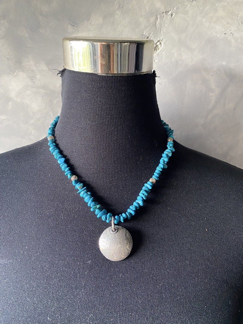 Turquoise and silver necklace (Category: Necklaces) located in Cebu City. Submitted by janb85 (Listing ID 1459666950, Image 1). Description: A turquoise-like chip bead necklace featuring a round engraved metal pendant and textured silver toned spacers No identifiable marking. Natural stone but untested if real turquoise or not. Pendant is substantial and weighty but also untested for silver. Chips have a deeper blue color than the normal brighter