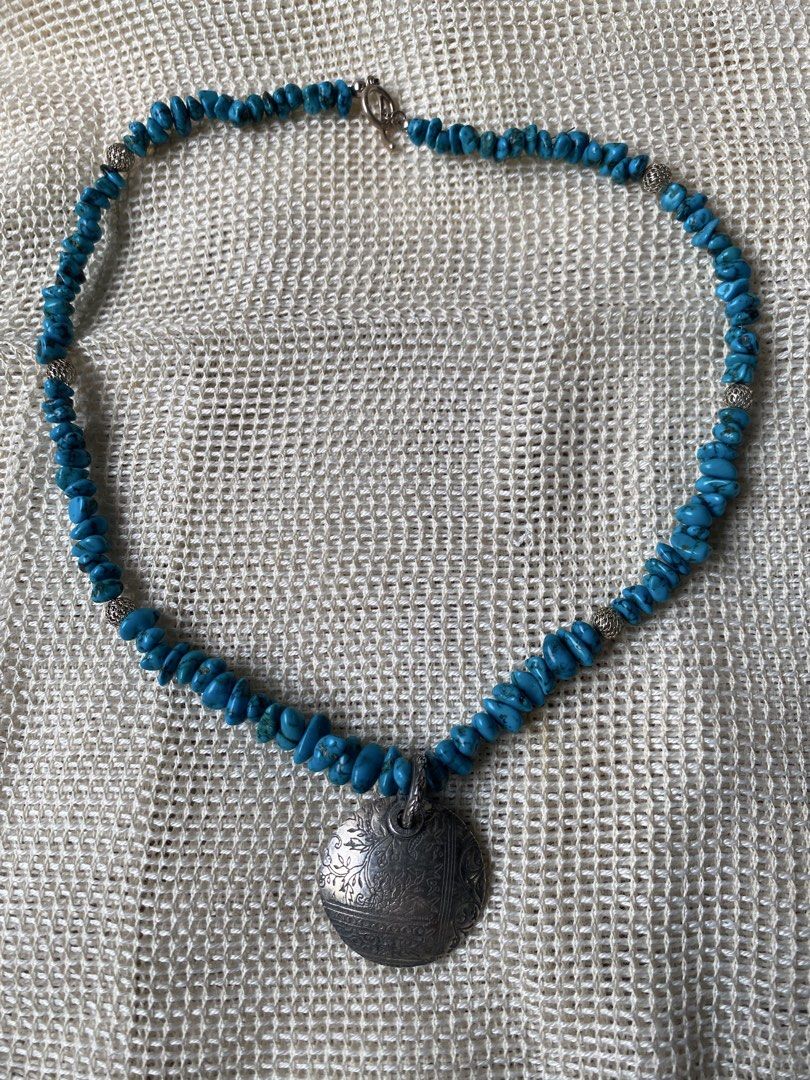 Turquoise and silver necklace (Category: Necklaces) located in Cebu City. Submitted by janb85 (Listing ID 1459666950, Image 3). Description: A turquoise-like chip bead necklace featuring a round engraved metal pendant and textured silver toned spacers No identifiable marking. Natural stone but untested if real turquoise or not. Pendant is substantial and weighty but also untested for silver. Chips have a deeper blue color than the normal brighter