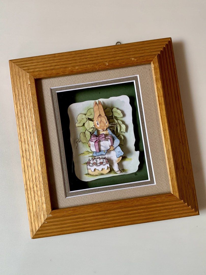 vintage Peter Rabbit 3D decoupage art piece - wallframe (Category: Wall Decor) located in Tandag. Submitted by jeason_22 (Listing ID 1459593049, Image 1). Description: Design Features Style: 3D decoupage or shadow box art, where paper layers are cut and stacked to create depth. Scene: Peter Rabbit wears his classic blue jacket, holds a wrapped gift with a pink bow, and stands near a small birthday cake with candles. Frame: Set inside a textured, 