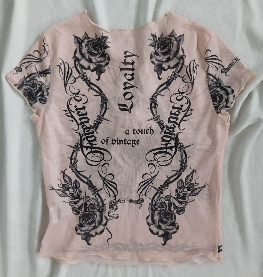 Y2k Shein Tattoo Mesh Top (Category: Shirts) located in Angeles City. Submitted by itsandspreloved (Listing ID 1459582329, Image 2). Description: - Sheer pink mesh fabric - Bold tattoo-inspired graphic on front: roses, heart, 'Loyalty' - Back design: 'Loyalty' and 'Forever' text with barbed wire and rose motifs - Lettuce hem edges for a unique finish - Vintage-inspired, one-of-a-kind piece.