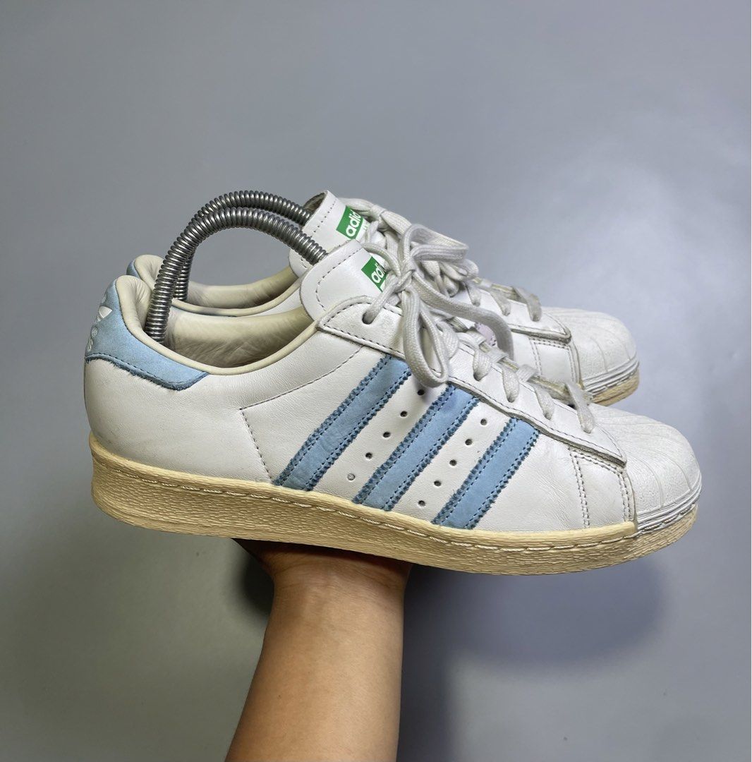 Adidas Superstar White Light Blue Stripes Shell Toe Sneakers (Category: Sneakers) located in Zamboanga. Submitted by laffthrift_23 (Listing ID 1459873785, Image 1). Description: - Classic Adidas Superstar sneakers - White leather with light blue stripes - Iconic shell toe design - Soles show some yellowing from age - Perfect for casual wear and vintage style.