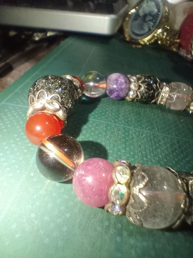 Beaded Bracelet with Charms and Gemstones (Category: Bracelets) located in Munoz. Submitted by larryc1212 (Listing ID 1459812932, Image 2). Description: - Unique beaded bracelet - Mix of large and small beads - Various colors and textures: clear with inclusions, purple stones, red stones, black speckled beads - Ornate silver-tone charms - Stretchy design for easy wear - Perfect statement piece for any outfit Disclaimer: Item may include some scra