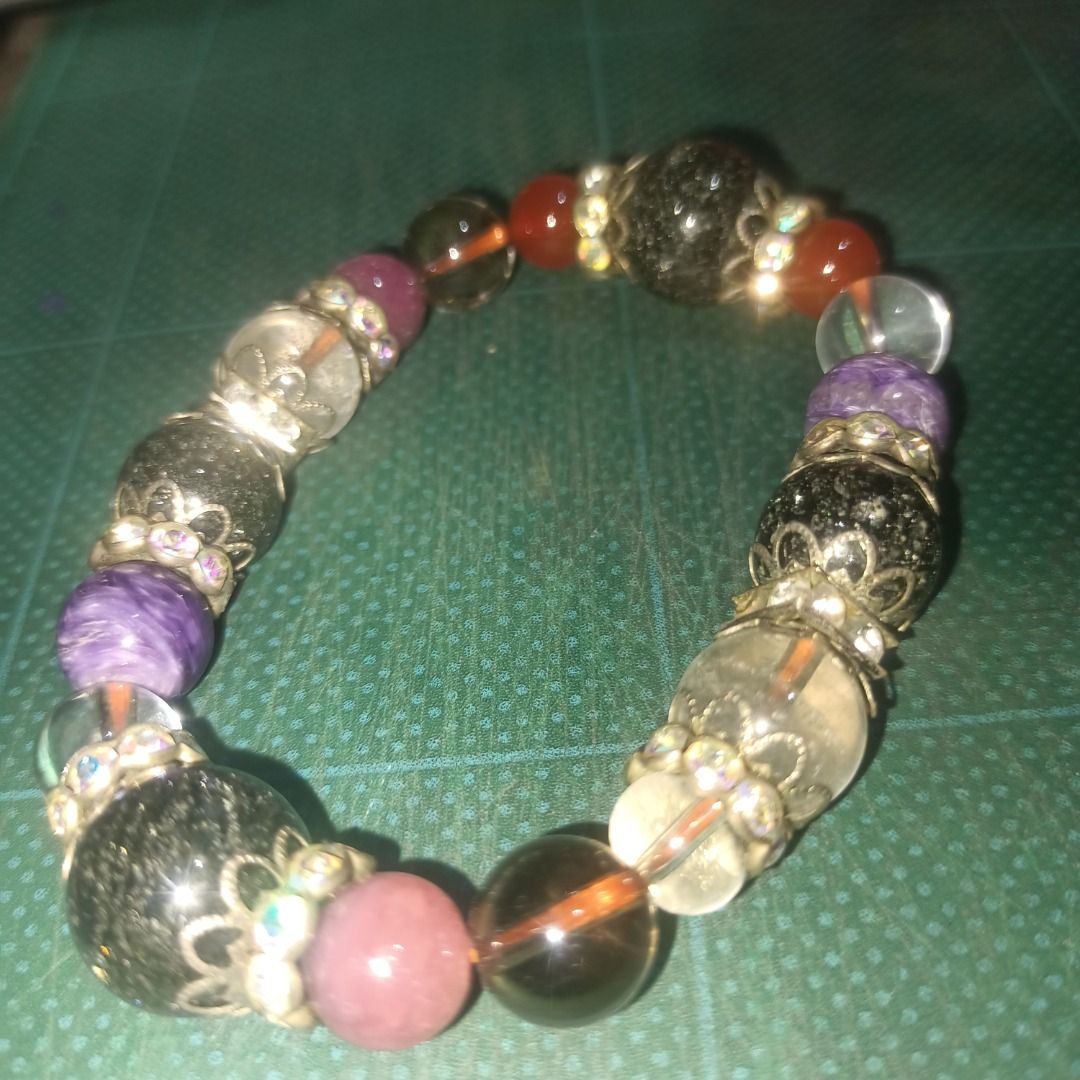 Beaded Bracelet with Charms and Gemstones (Category: Bracelets) located in Munoz. Submitted by larryc1212 (Listing ID 1459812932, Image 1). Description: - Unique beaded bracelet - Mix of large and small beads - Various colors and textures: clear with inclusions, purple stones, red stones, black speckled beads - Ornate silver-tone charms - Stretchy design for easy wear - Perfect statement piece for any outfit Disclaimer: Item may include some scra