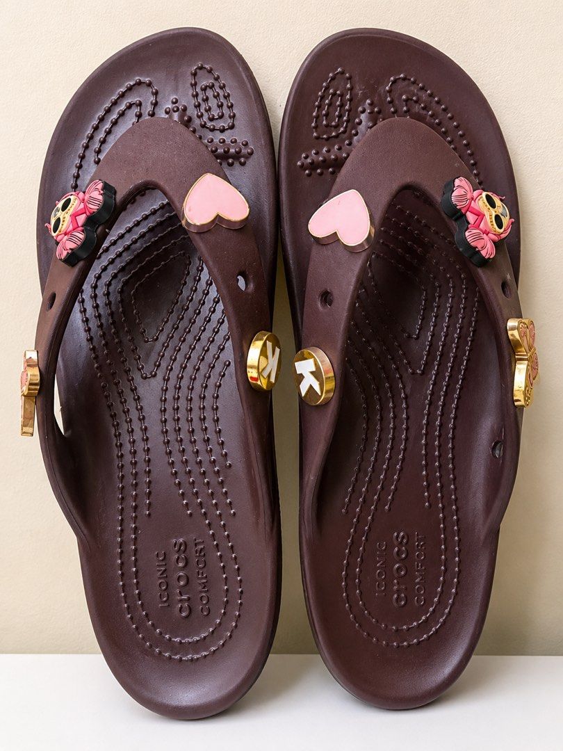 Brown Crocs Flip-flops with Charms (Category: Slippers and slides) located in San Fernando. Submitted by currency_sy (Listing ID 1459865431, Image 1). Description: - Brown Crocs flip-flops - Decorated with pink hearts and owl charms - Features gold 'K' initial charms - Comfortable and iconic Crocs style - Ideal for casual wear.