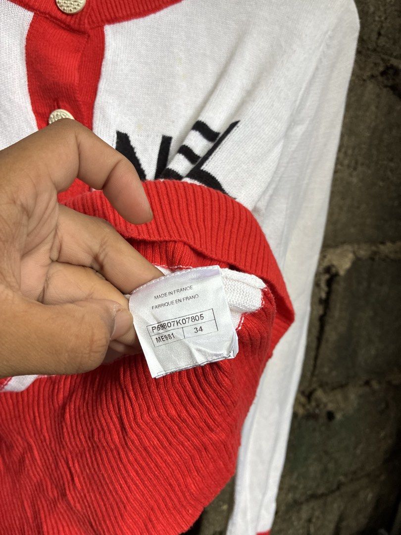 Chanel White Red Logo Button Cardigan (Category: Luxury Apparel) located in Manila. Submitted by assortedgoodsv3 (Listing ID 1459720069, Image 3). Description: - Classic Chanel cardigan - Color: White with red trim and cuffs - Features Chanel logo on buttons - Bold 'CHANEL' lettering across the front - Made in France - Size: 34 - Perfect for fashion enthusiasts.