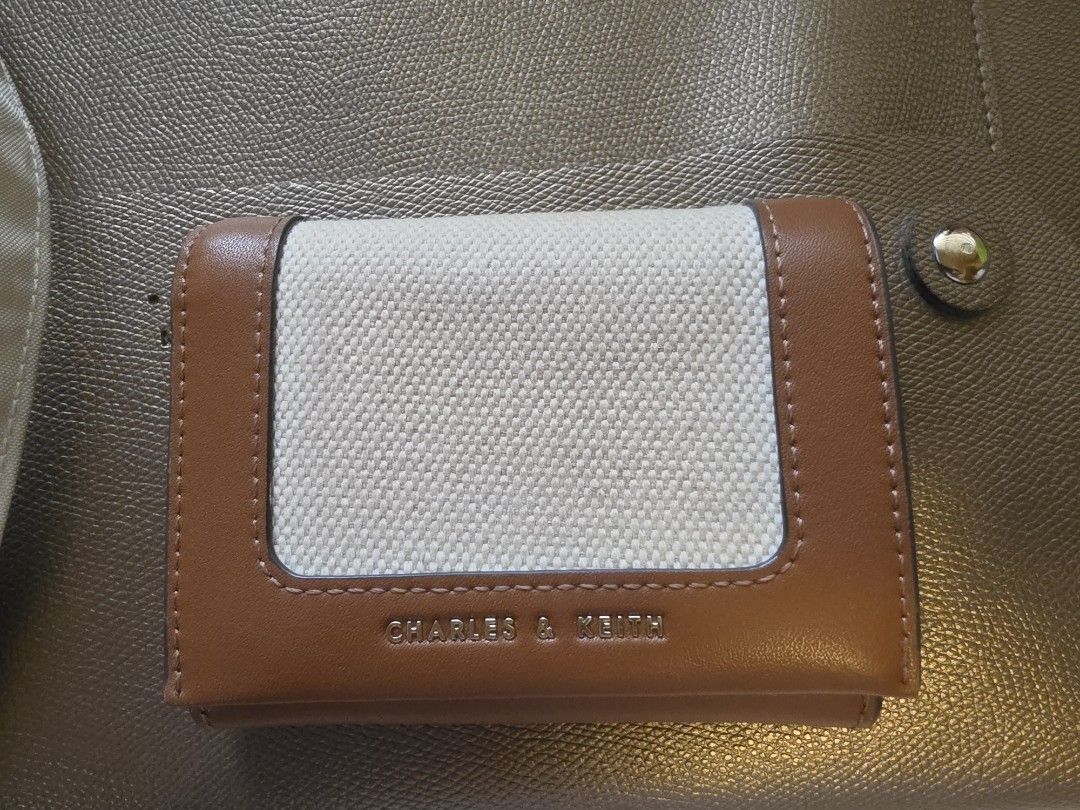 Charles & Keith Brown Canvas Tri-fold Wallet (Category: Wallets & Card holders) located in Manila. Submitted by philgabjhn (Listing ID 1459757731, Image 1). Description: - Brand: Charles & Keith - Color: Brown and Cream - Style: Tri-fold wallet - Material: Canvas front panel with faux leather trim - Interior: Card slots and zippered coin pocket - Closure: Snap button - Size: Compact, fits easily in pockets and small bags .