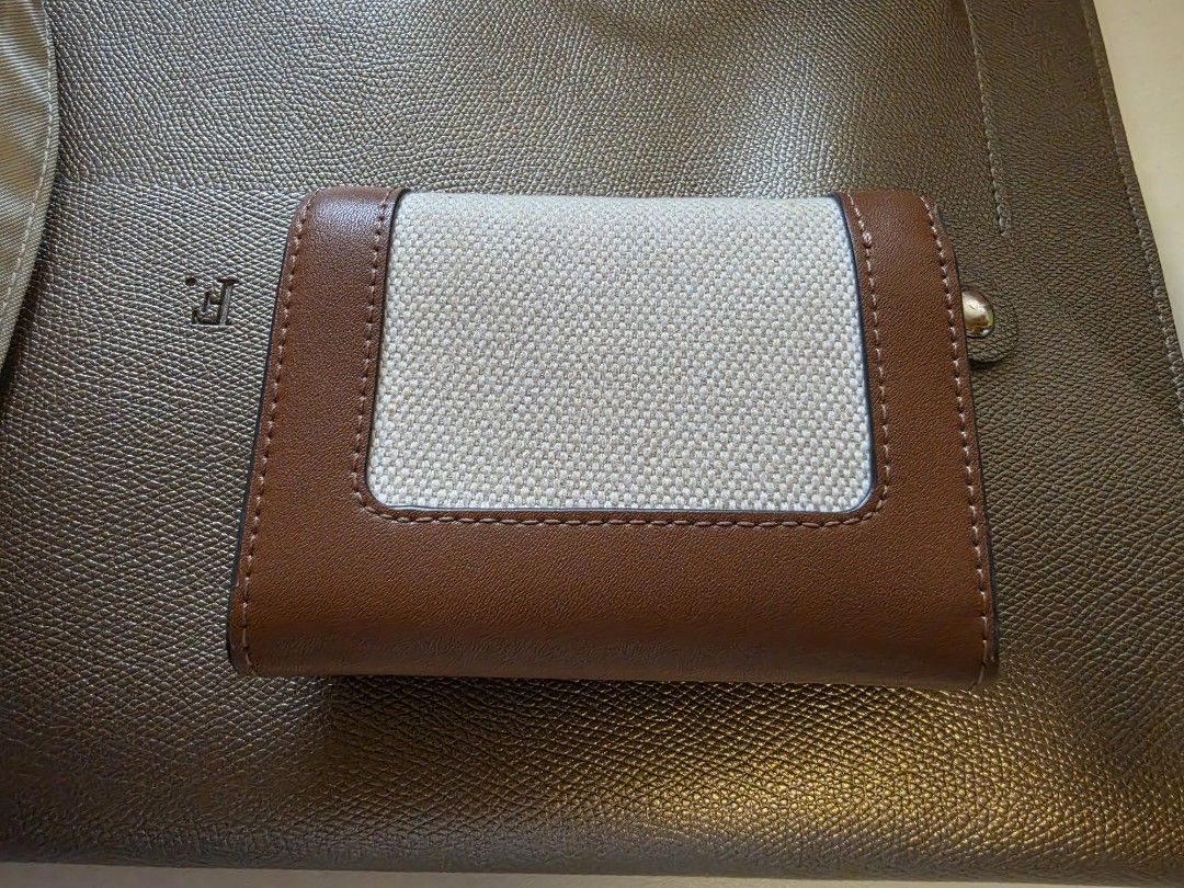 Charles & Keith Brown Canvas Tri-fold Wallet (Category: Wallets & Card holders) located in Manila. Submitted by philgabjhn (Listing ID 1459757731, Image 2). Description: - Brand: Charles & Keith - Color: Brown and Cream - Style: Tri-fold wallet - Material: Canvas front panel with faux leather trim - Interior: Card slots and zippered coin pocket - Closure: Snap button - Size: Compact, fits easily in pockets and small bags .