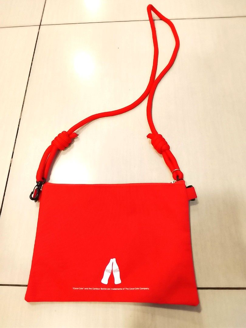 Coca-Cola Red Canvas Sling Pouch Bag (Category: Purses & Pouches) located in Manila. Submitted by newage.vintage (Listing ID 1459804748, Image 2). Description: - Red Coca-Cola pouch bag - Adjustable red rope strap - Zipper closure - Ideal for carrying essentials - Iconic Coca-Cola logo on the front - Simple back design with two white contour bottles - Great for casual outings.