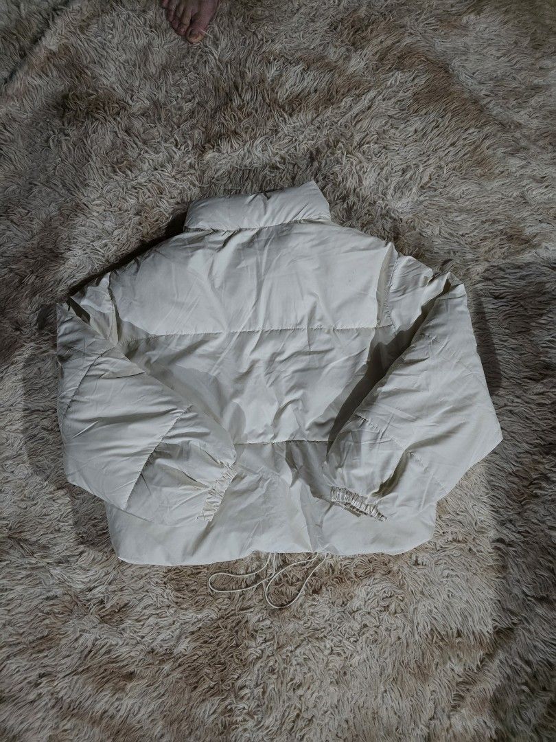 Off-White Cropped Puffer Jacket with Drawstring Hem (Category: Coats, Jackets and Outerwear) located in Paranaque City. Submitted by ccc_finds (Listing ID 1459822550, Image 2). Description: • Off-white cropped puffer jacket • Drawstring hem for adjustable fit • Button-up front with convenient pockets • Measurements: Shoulder - 20 in. Chest width - 24 in. Jacket length - 21 in. Sleeve length - 22 in. Arms sleeve width - 9 in. • Condition: Used onc