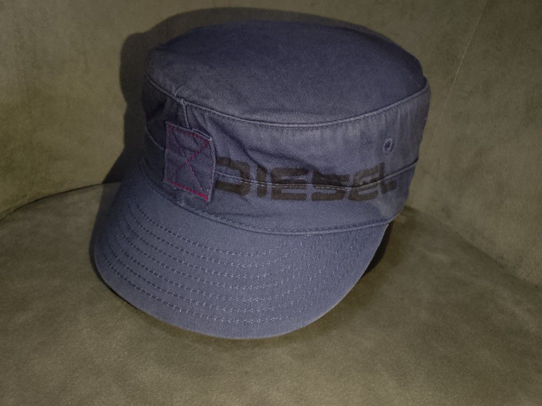 Diesel Cadet Cap S-M (Category: Caps & Hats) located in Binangonan. Submitted by yuristalin888 (Listing ID 1459803822, Image 3). Description: Elevate your everyday casual style with this dark grayish blue Diesel cadet cap. Crafted from durable cotton twill, this utility-inspired flat-top hat features a classic curved brim and embroidered eyelets for breathability. It is accented with the bold "DIESEL" logo across the front and finished with a dis