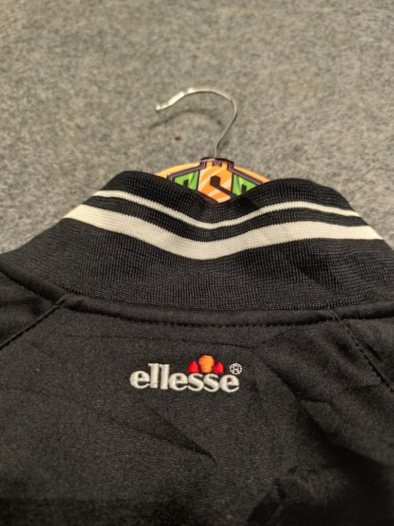 Ellesse Black Track Jacket with Red Piping (Category: Coats, Jackets and Outerwear) located in Cordova. Submitted by bsb.streetluxvintage.clothing (Listing ID 1459797764, Image 3). Description: - Classic black Ellesse track jacket - Red piping along the sides - White striped cuffs and collar - Full zip closure - Embroidered Ellesse logo on chest and back - Ideal for casual wear or sports.