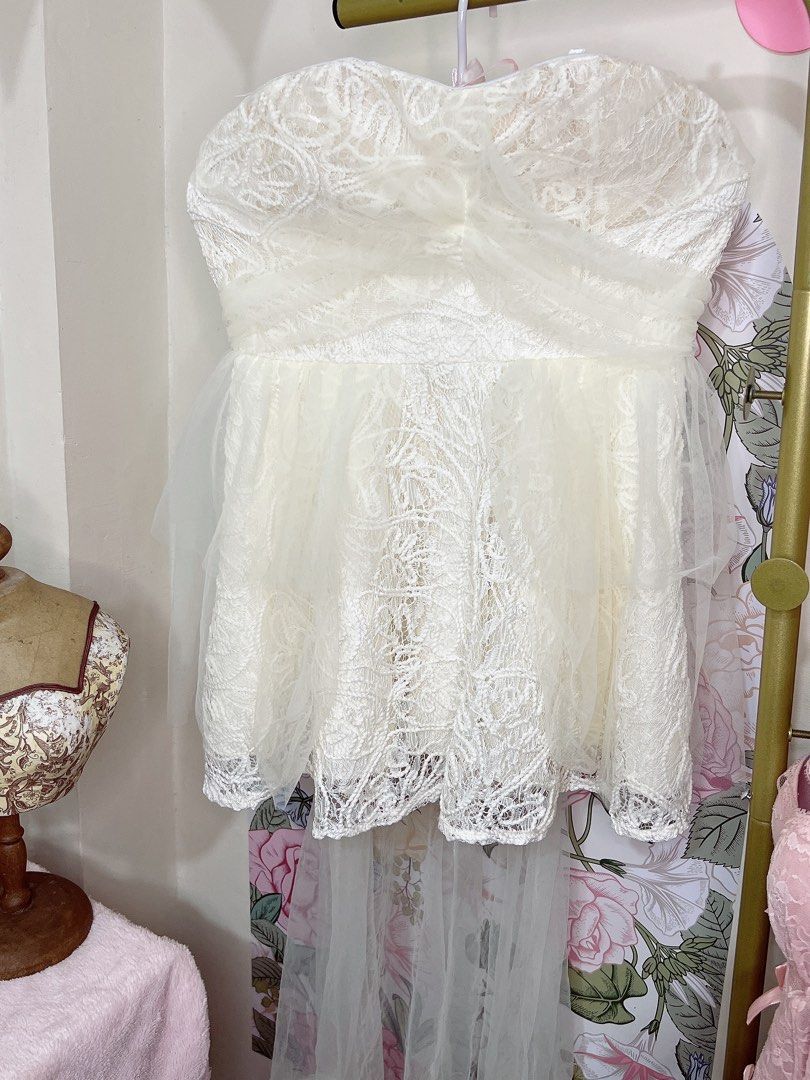 For rent * Ivory White dress (Category: Dresses) located in Cavite. Submitted by wishie_collects (Listing ID 1459818008, Image 3). Description: This is a short, white, strapless dress with a sweetheart neckline. The bodice and skirt are made of a sheer, lace-like overlay featuring intricate, swirling cord embroidery over a white lining. The skirt has a voluminous, layered tulle overlay. The dress is cut above the knees, and an additional layer of
