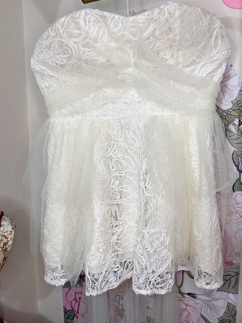 For rent * Ivory White dress (Category: Dresses) located in Cavite. Submitted by wishie_collects (Listing ID 1459818008, Image 2). Description: This is a short, white, strapless dress with a sweetheart neckline. The bodice and skirt are made of a sheer, lace-like overlay featuring intricate, swirling cord embroidery over a white lining. The skirt has a voluminous, layered tulle overlay. The dress is cut above the knees, and an additional layer of
