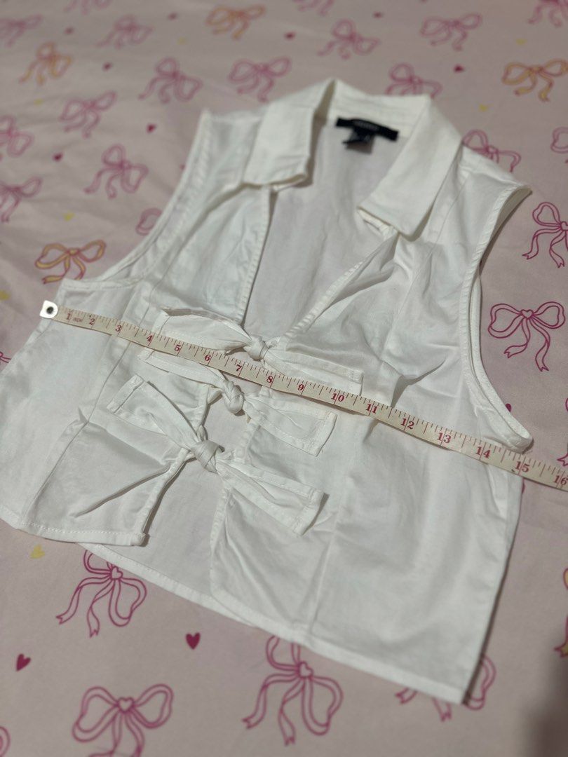 Forever 21 White Sleeveless Cropped Collared Top with Bows (Category: Sleeveless) located in Daet. Submitted by 614cb (Listing ID 1459719210, Image 2). Description: - White sleeveless crop top - Brand: Forever 21 - Features: Collared neckline, V-cut front with 3 bow details - Back: Plain - Measurements: Approx. 15 inches across the chest Used once Has stains can be seen in the photos due to storage Still very pretty Rfs: been wfh and seldom goes 