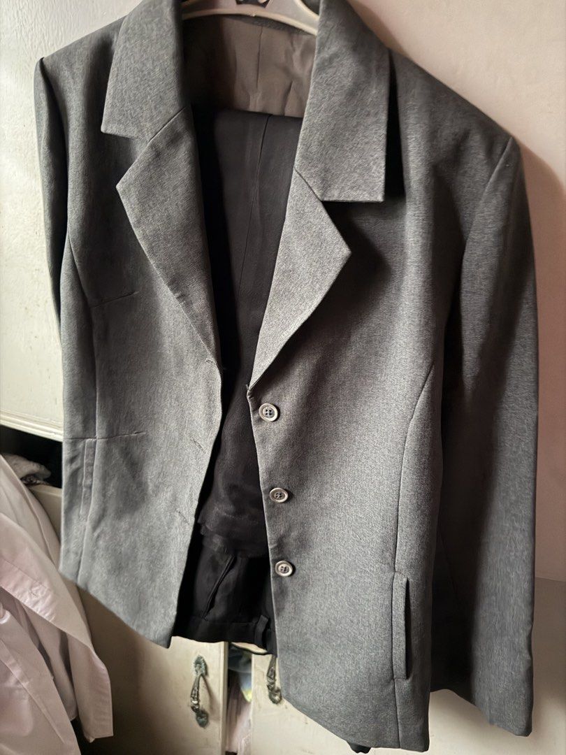 Grey Two-Button Blazer (Category: Coats, Jackets and Outerwear) located in Binan City. Submitted by im_chelie (Listing ID 1459750673, Image 1). Description: - Classic grey blazer - Two-button front closure - Two front flap pockets - Fully lined interior - Versatile for formal or casual wear.