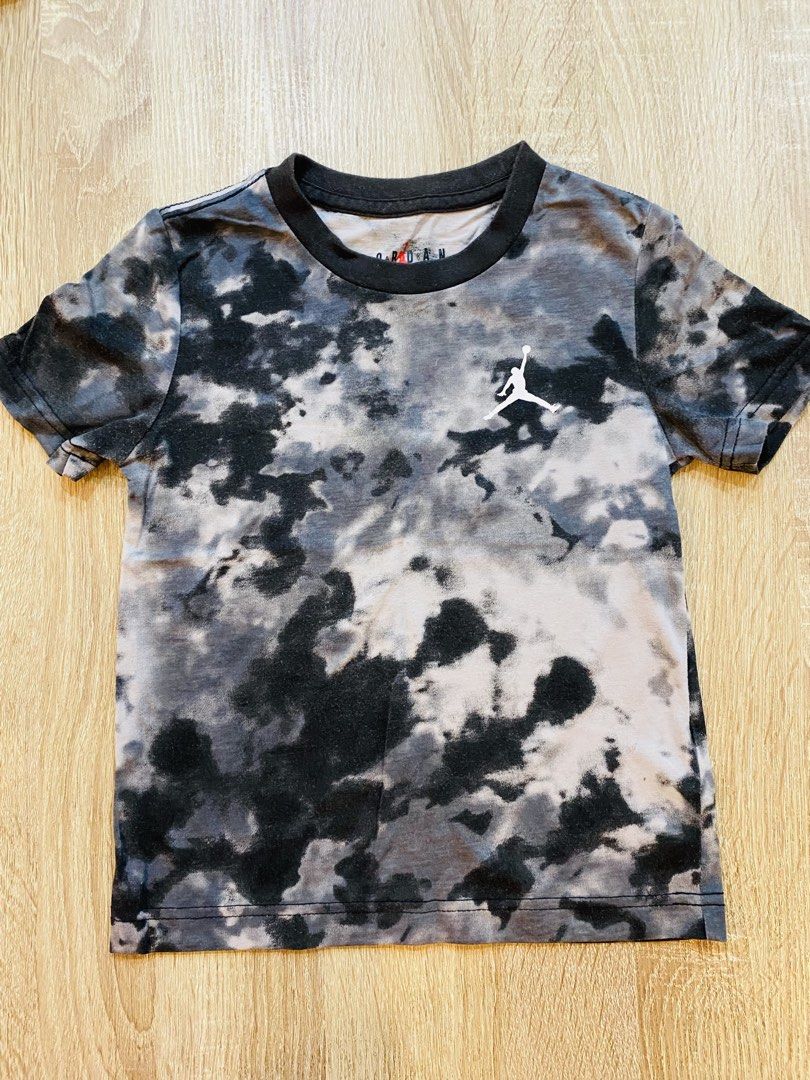 Jordan Tie-Dye T-Shirt (Category: Babies & Kids Fashion) located in Indang. Submitted by matilde.sshop (Listing ID 1459886813, Image 1). Description: - Authentic Jordan tie-dye t-shirt - Features iconic Jumpman logo - Stylish black, grey, and white pattern - Classic short sleeves and crew neck design - Ideal for everyday casual wear.