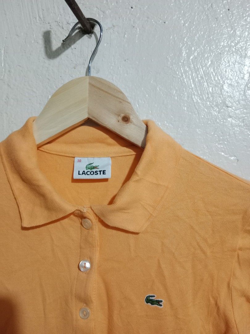 Lacoste Orange Polo Shirt (Category: Blouses) located in Toledo. Submitted by zealzionta54269 (Listing ID 1459743464, Image 2). Description: - Orange Lacoste Polo Shirt - Short sleeves - Collared neckline with button-up front - Iconic embroidered Lacoste crocodile logo on chest - Comfortable cotton blend fabric - Ideal for casual outings and everyday wear -width 16-17 length 22.