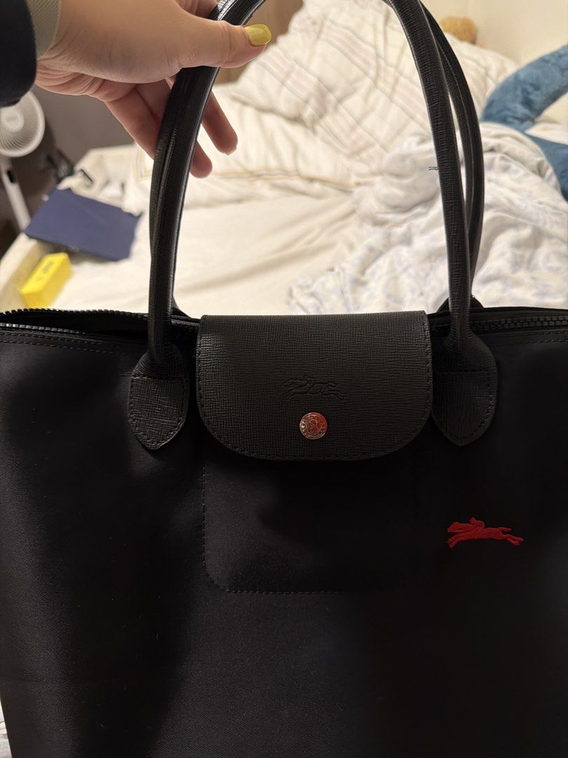 Longchamp Le Pliage Tote Bag Black (Category: Luxury Bags & Wallets) located in Manila. Submitted by shobeshop_ (Listing ID 1459842403, Image 3). Description: - Classic black Longchamp tote bag - Durable nylon body with genuine leather handles and trim - Features the iconic red horse logo - broken zipper closure with a snap-tab flap ( can repair) - Includes an interior pocket for organization - Ideal everyday bag for carrying essentials - please 